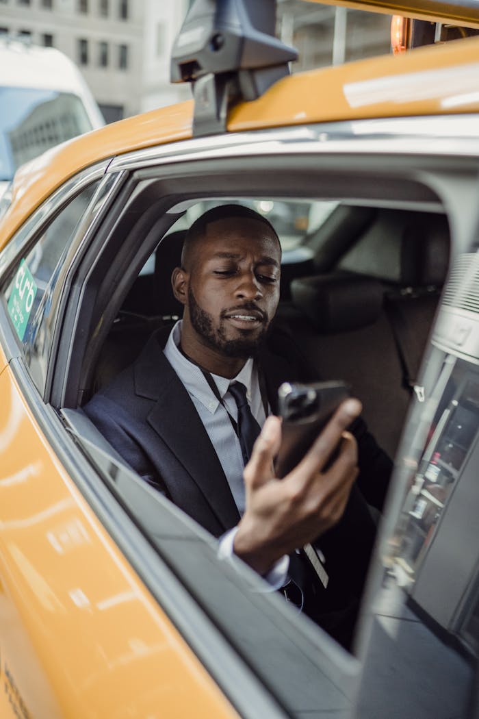 Crafting Captivating Headlines: Your awesome post title goes here Young man in suit using phone inside a taxi in an urban setting. Daylight.